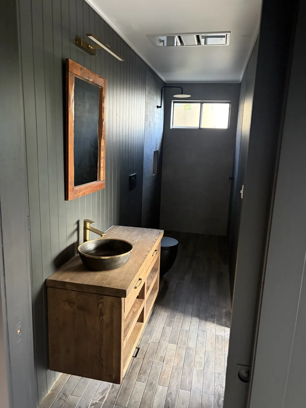 Finished bathroom featuring timber vanity and dark fixtures